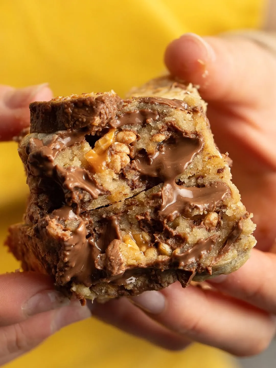 Un cookie bar Lion au cœur fondant, tenu à deux mains, chocolat coulant
